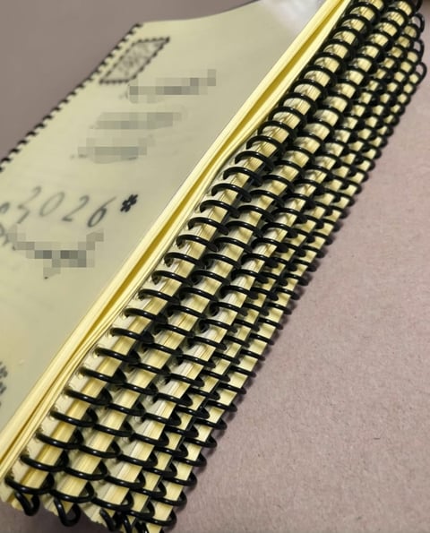Close-up of spiral-bound notebook with cream-colored pages and gold metal binding along the edge
