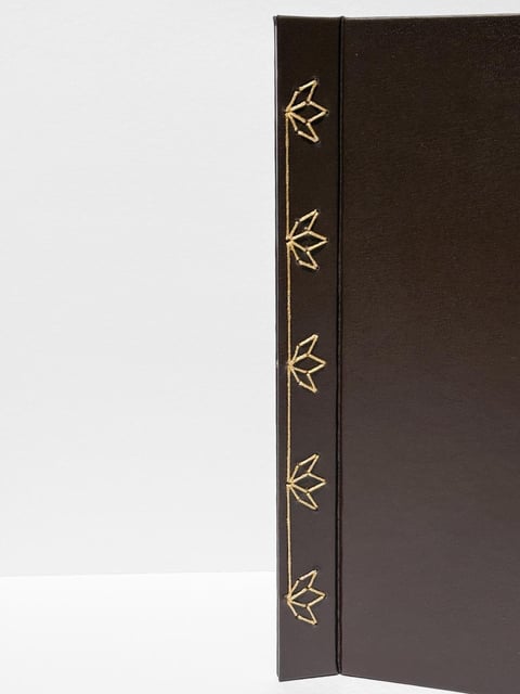 Black hardcover book spine with gold leaf decorative motifs arranged vertically