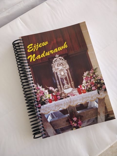 Spiral-bound notebook with Eijew Madurawah title, featuring ornate crystal lantern and pink floral decorations on wooden table