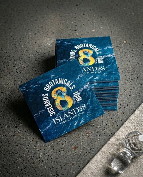 Stack of blue Islands Botanicals business cards with gold number 8 logo on concrete surface