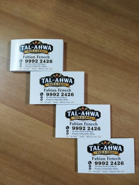 Four business cards for Tal-Ahwa Pub and Grill with Fabian Fenechs contact details arranged on a wooden surface
