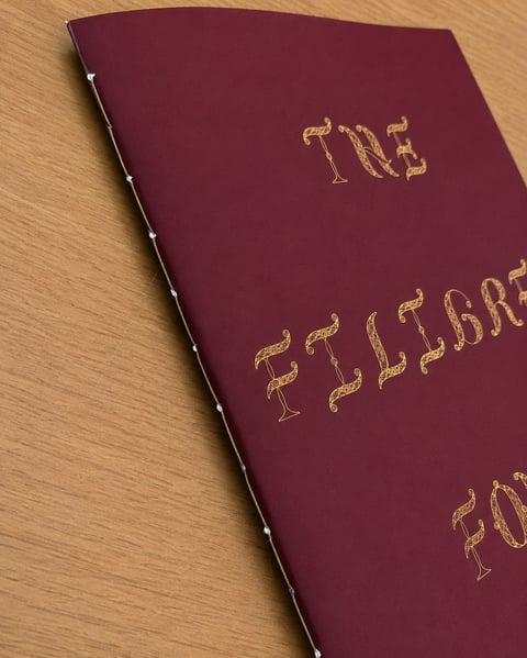 Burgundy book with gold embossed text on wooden surface, appears to be a celebrate-themed volume