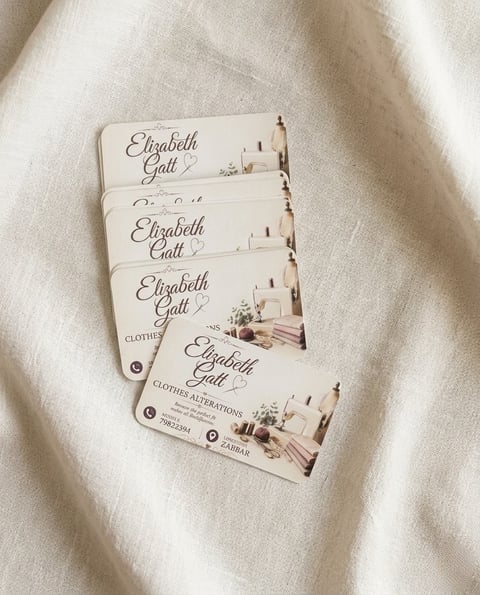 Stack of Elizabeth Gall clothing tags on cream fabric background