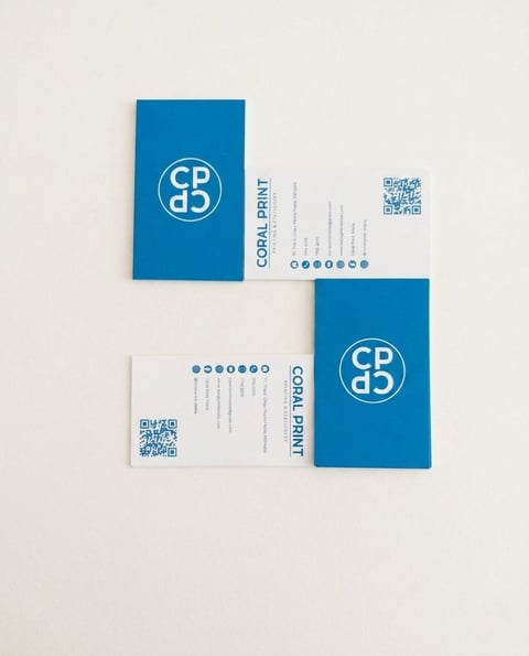 Coral Print business cards and materials with blue design, logo, contact details, and QR codes on cream background