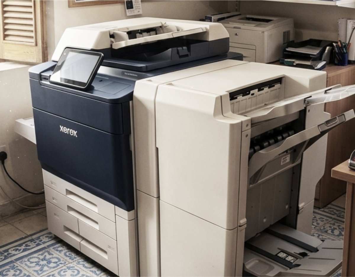 Office room with multiple multifunction printers and copiers, including a Xerox machine and beige-colored devices arranged on a patterned floor