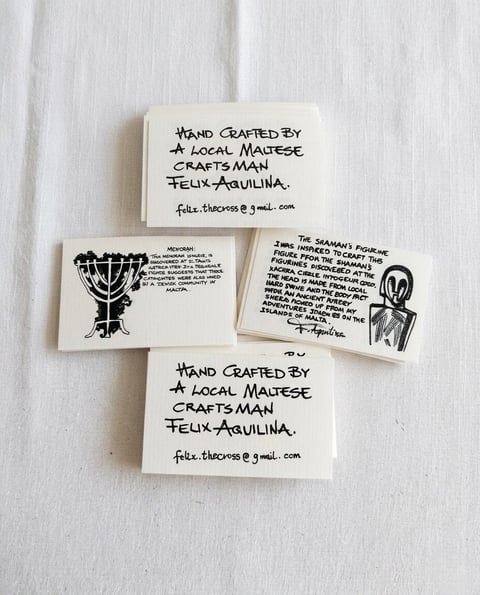 Handmade business cards by Felix Aguilina displayed on white linen, showing artisan branding with black ink drawings and contact details